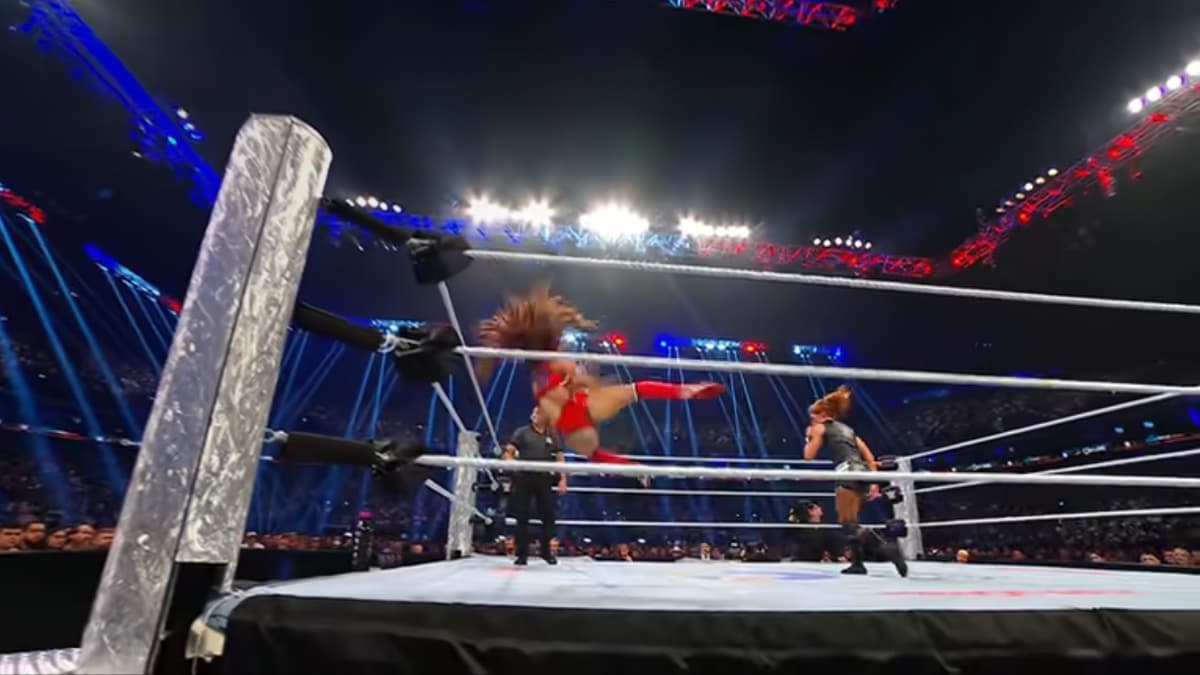Nikki Bella falling to the ring after missing a kick as Becky Lynch stands away from her