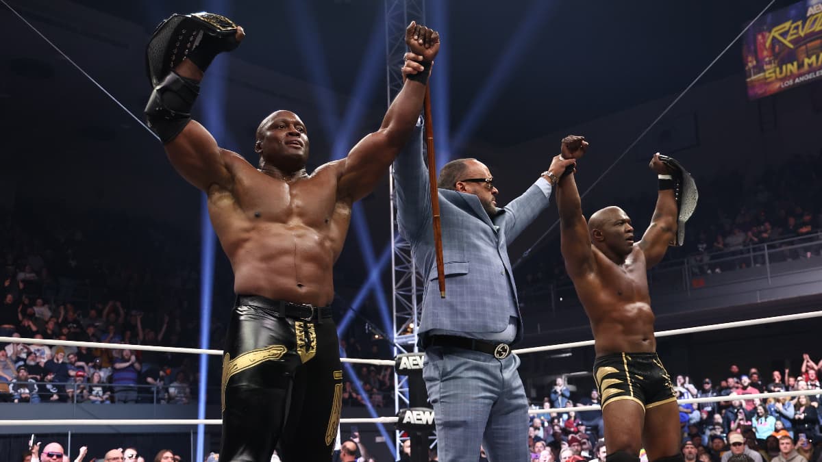 Bobby Lashley, MVP, and Shelton Benjamin celebrate a victory whilst holding championship belts in an AEW ring.