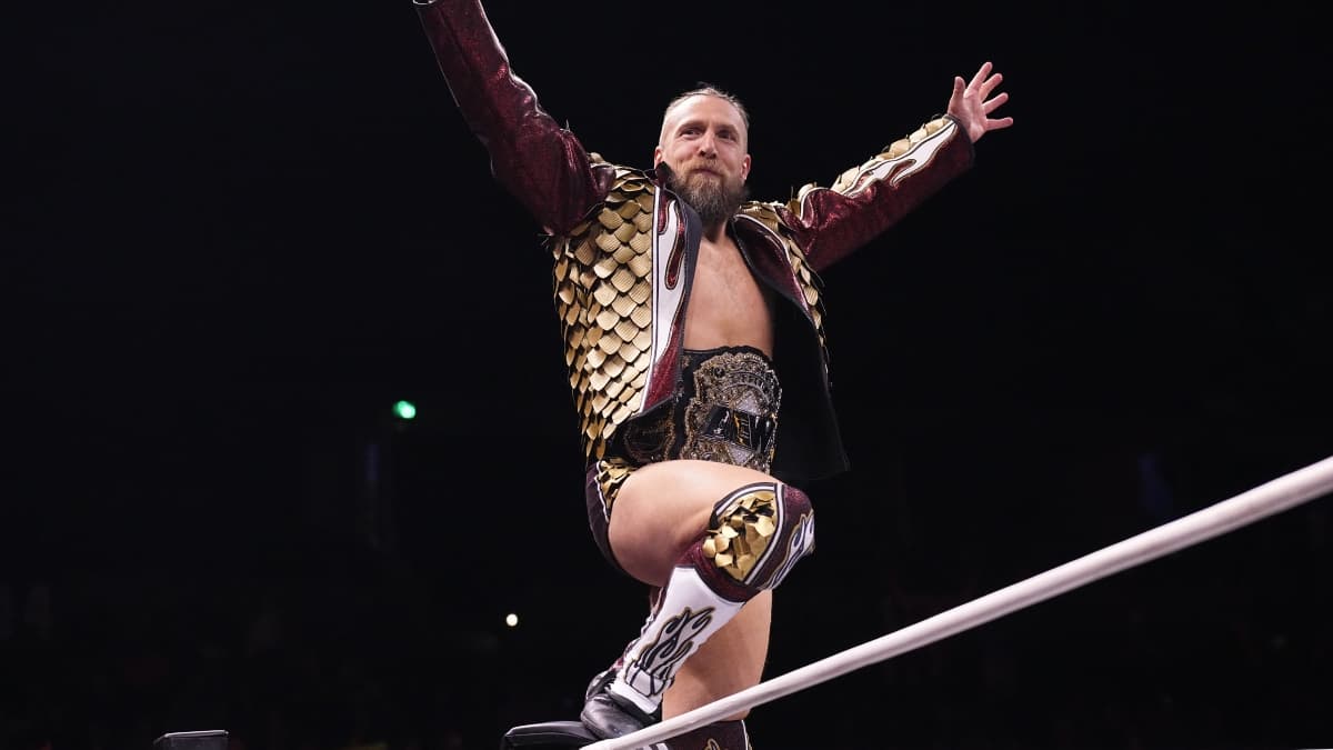 Bryan Danielson in a red dragon jacket on the turnbuckle with his arms outstretched